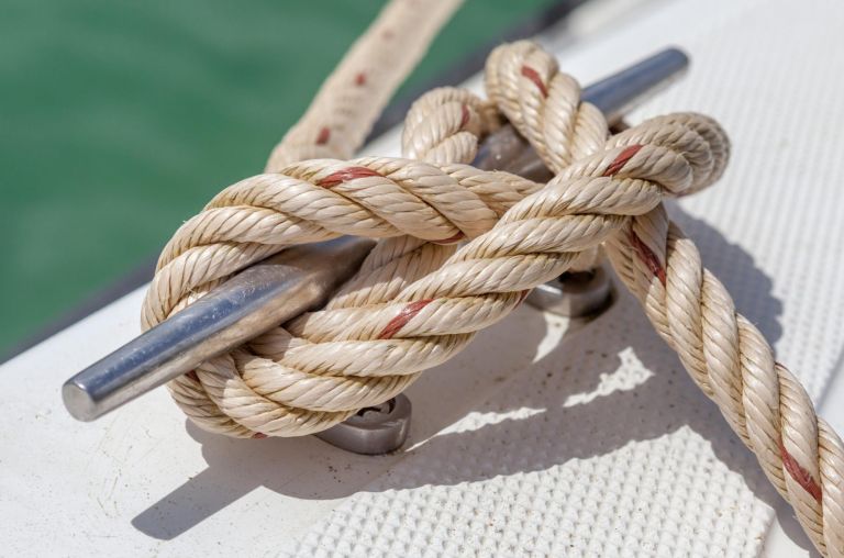 Close-up nautical knot rope tied around stake on boat or ship, boat mooring rope